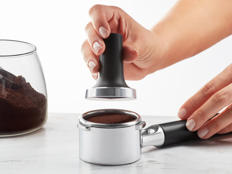 Hand tamping coffee grounds into portafilter Hand tamping coffee grounds into portafilter