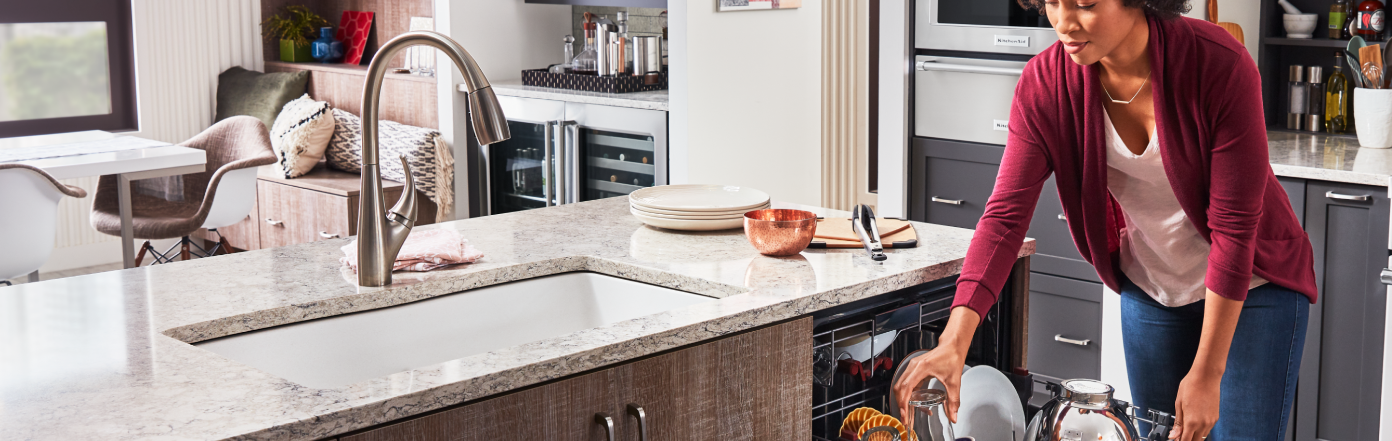 Person loading dishes into a dishwasher next to a kitchen sink