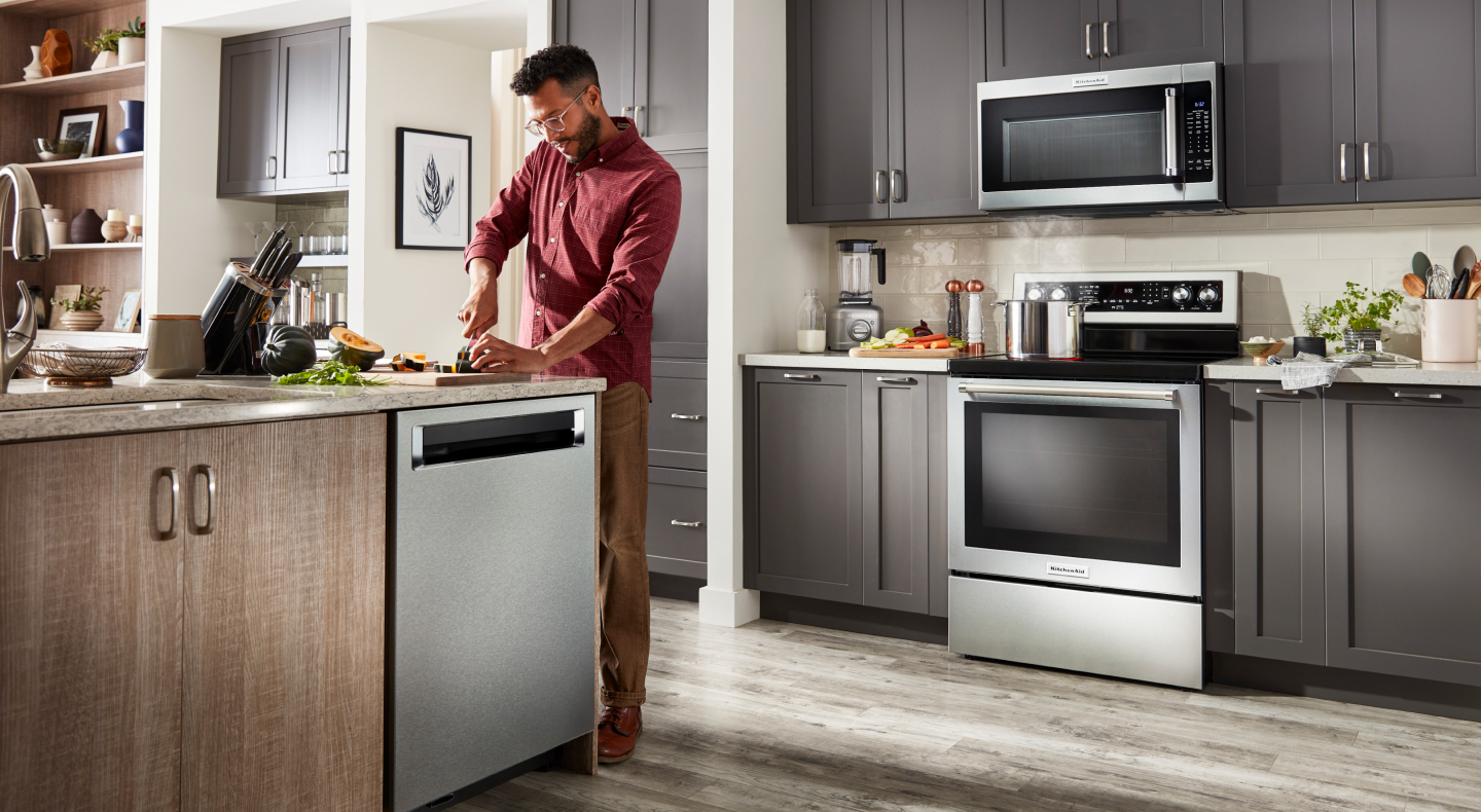 Person chopping veggies in a kitchen with a suite of KitchenAid® appliances  Person chopping veggies in a kitchen with a suite of KitchenAid® appliances