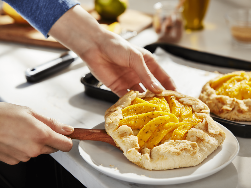 Hands placing homemade apple galette on a plate Hands placing homemade apple galette on a plate