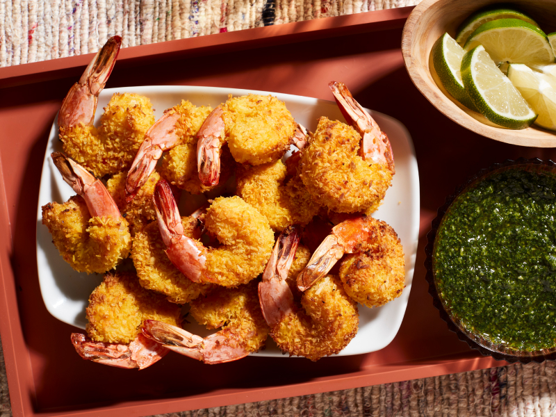 A closeup of air fryer shrimp on a serving tray next to a fresh sauce and lime slices. A closeup of air fryer shrimp on a serving tray next to a fresh sauce and lime slices.