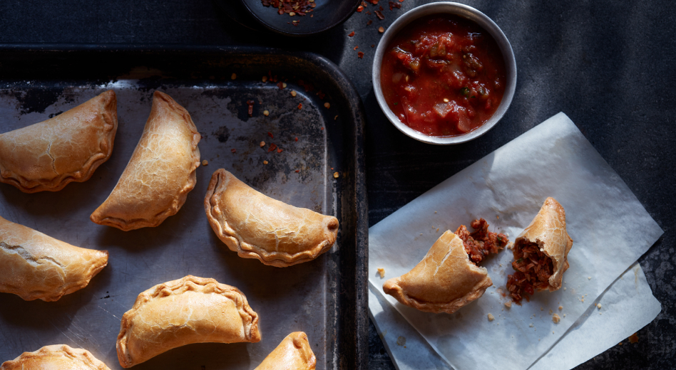 Empanadas on baking pan and on countertop with salsa Empanadas on baking pan and on countertop with salsa