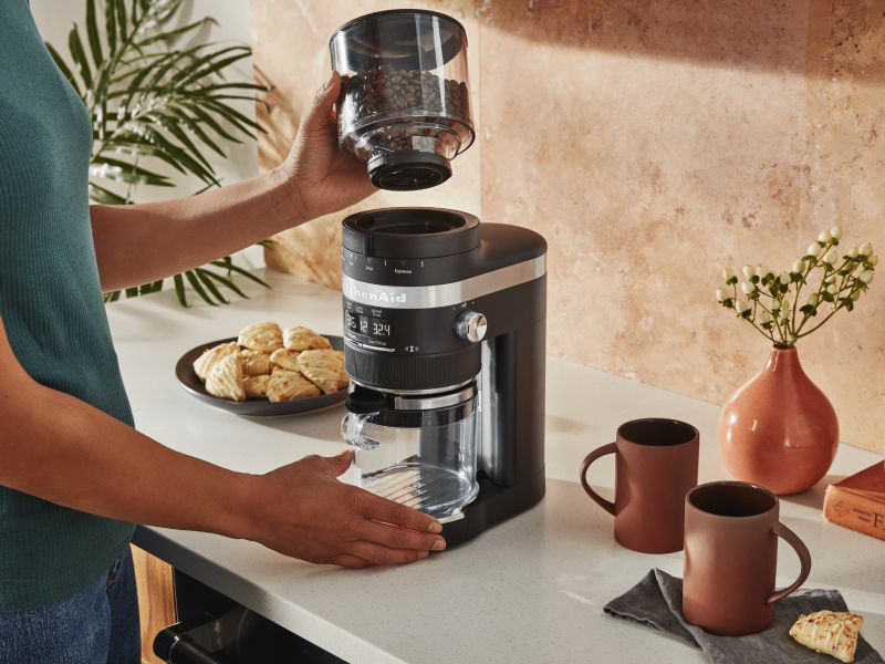 Woman placing top of coffee grinder on base of grinder Woman placing top of coffee grinder on base of grinder