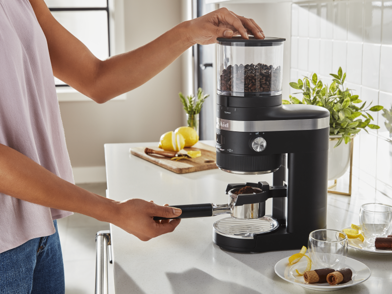 Woman removing portafilter with fresh coffee from KitchenAid® Burr Coffee Grinder Woman removing portafilter with fresh coffee from KitchenAid® Burr Coffee Grinder