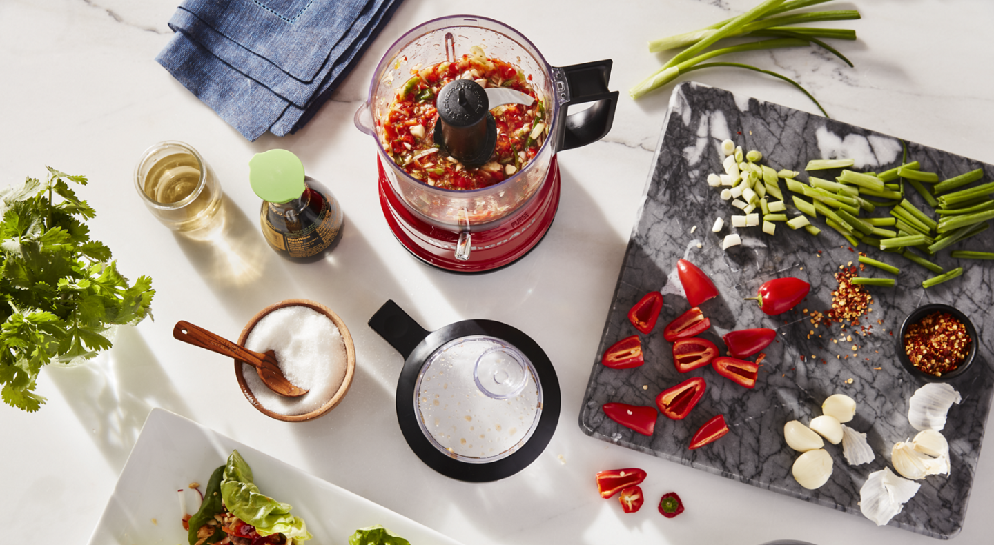 Vegetables and herbs on a cutting board and in a food processor Vegetables and herbs on a cutting board and in a food processor