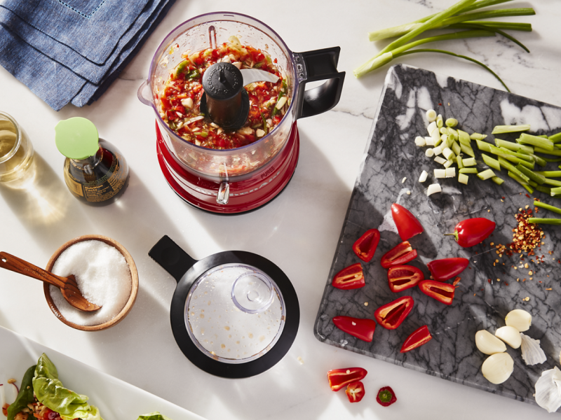 Vegetables and herbs on a cutting board and in a food processor Vegetables and herbs on a cutting board and in a food processor