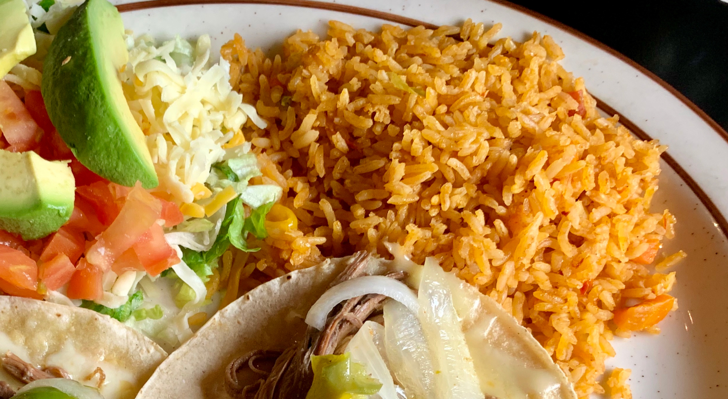 Seasoned rice on a plate with tacos and avocado Seasoned rice on a plate with tacos and avocado