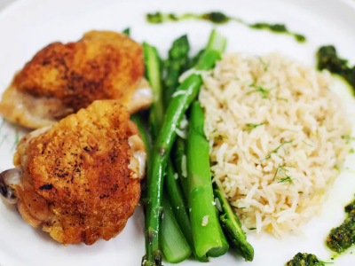 A plate of seasoned rice with asparagus and chicken.