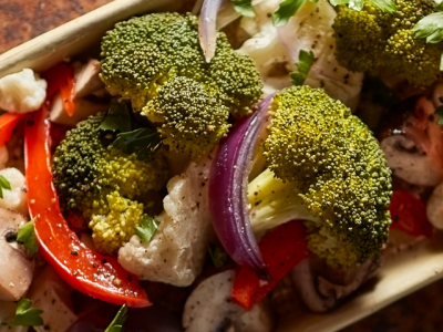 A closeup of fresh vegetables including broccoli, red pepper and red onion.