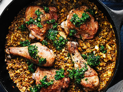 A cooking pan with chicken legs and seasoned rice.