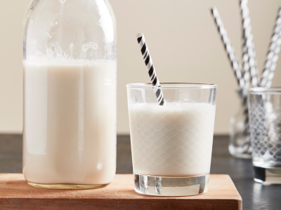 A closeup of a glass milk container next to a glass of milk.