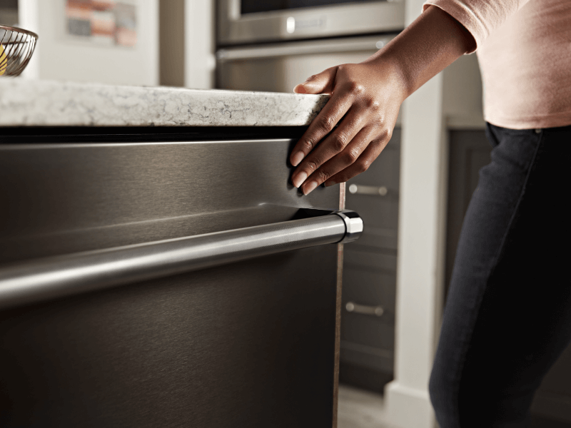 Person closing a KitchenAid® top control dishwasher Person closing a KitchenAid® top control dishwasher