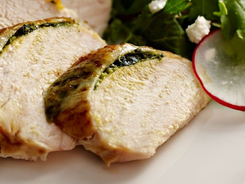 Close-up of a sliced meat dish next to a tossed salad