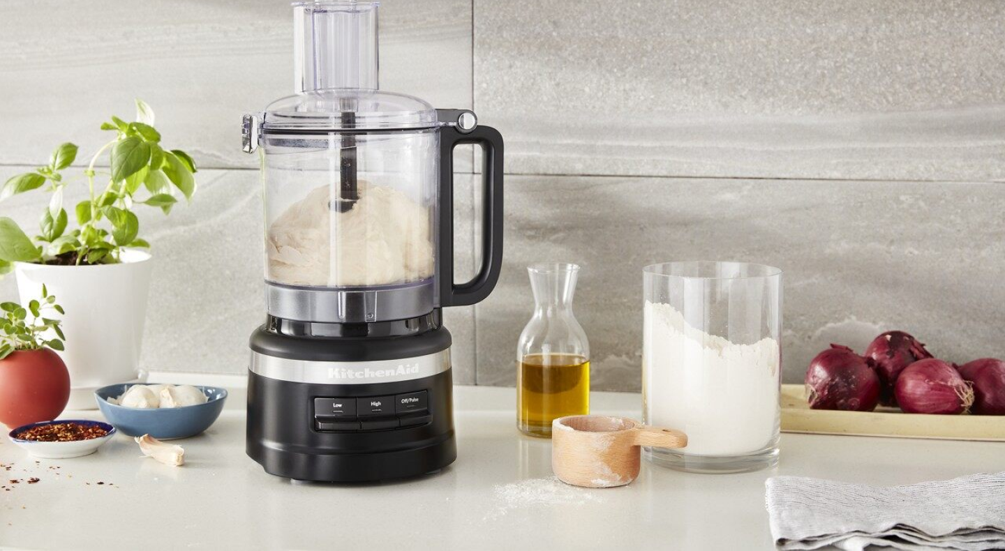 Food processor with dough inside and ingredients on countertop Food processor with dough inside and ingredients on countertop