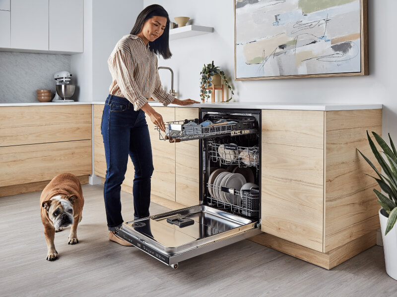 Person picking up dirty bowl to load into dishwasher Person picking up dirty bowl to load into dishwasher