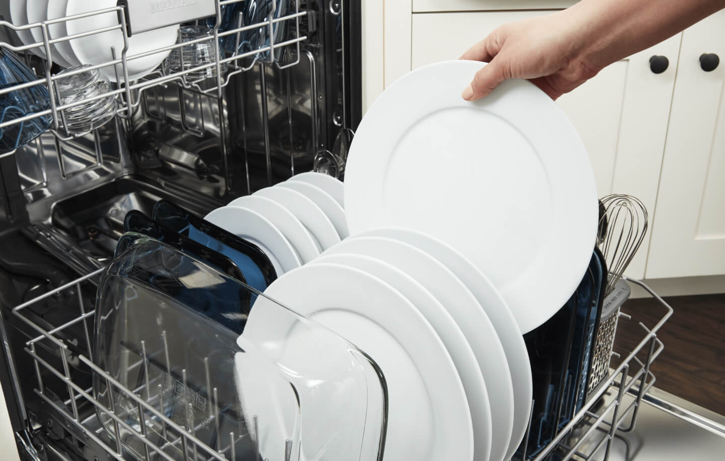 Person placing a white dish into a dishwasher Person placing a white dish into a dishwasher