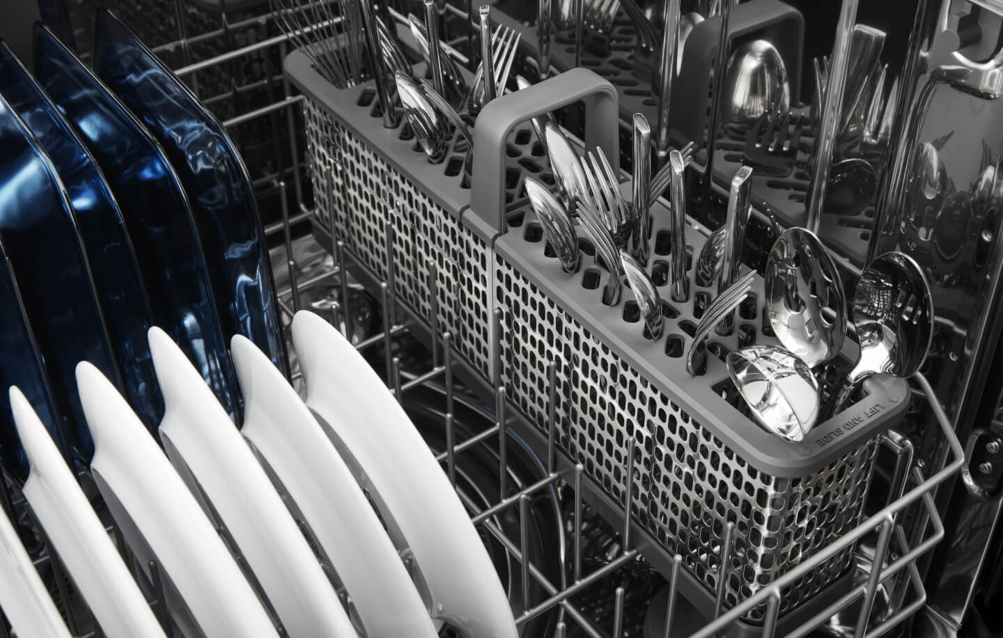 Clean plates and silverware in a dishwasher after a cycle Clean plates and silverware in a dishwasher after a cycle
