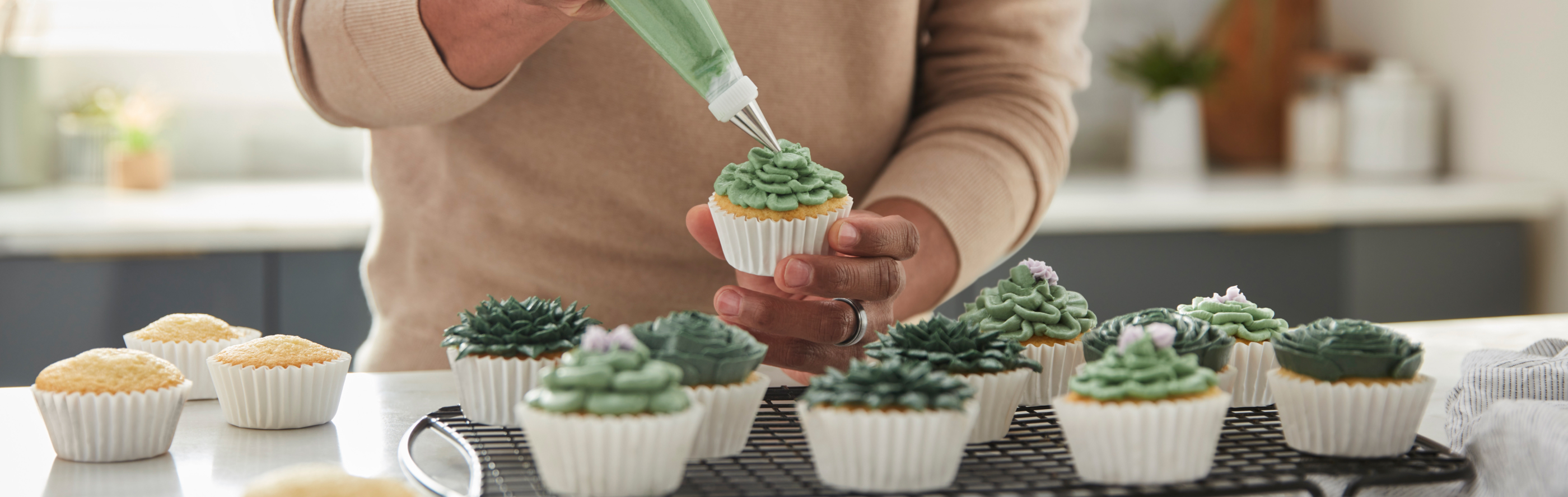 Person piping frosting onto a cupcake