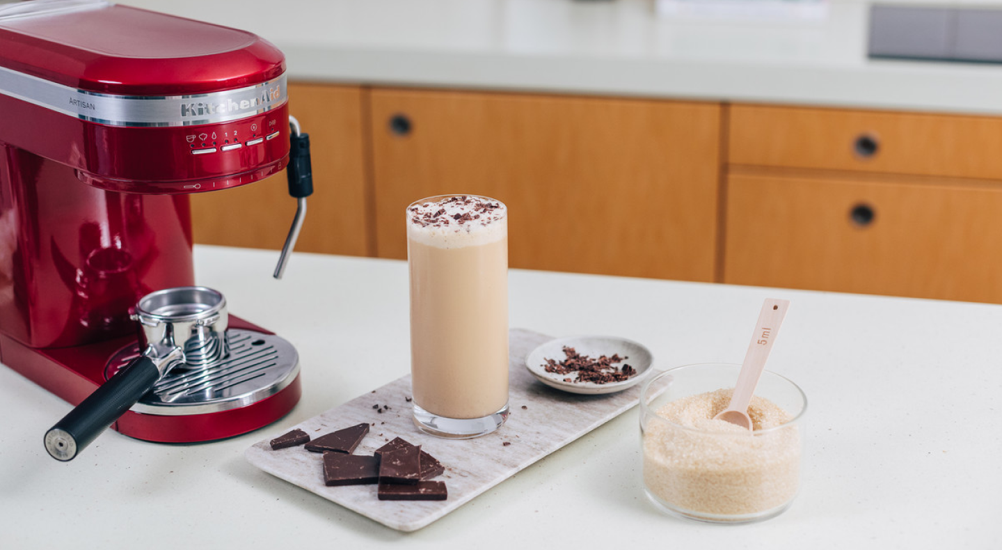 Frappe topped with chocolate shavings next to a KitchenAid® espresso machine