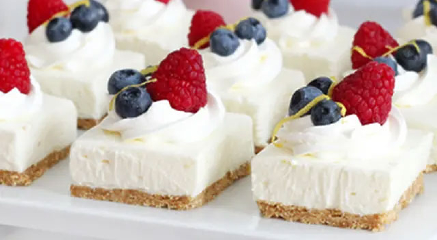 Cheesecake squares topped with whipped cream and fresh fruit Cheesecake squares topped with whipped cream and fresh fruit