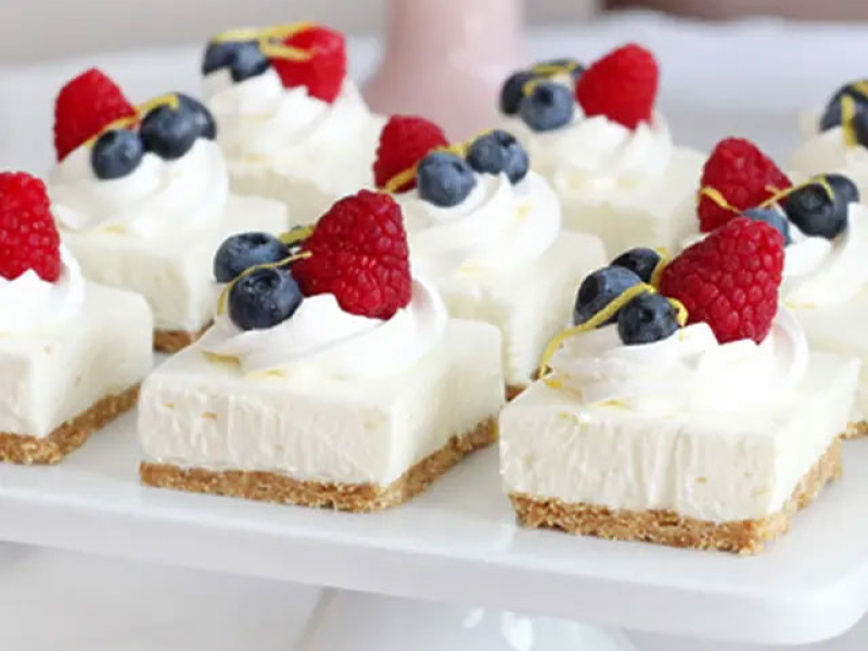 Cheesecake squares topped with whipped cream and fresh fruit Cheesecake squares topped with whipped cream and fresh fruit