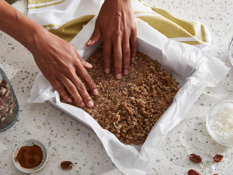 Person forming graham cracker crust in a baking dish