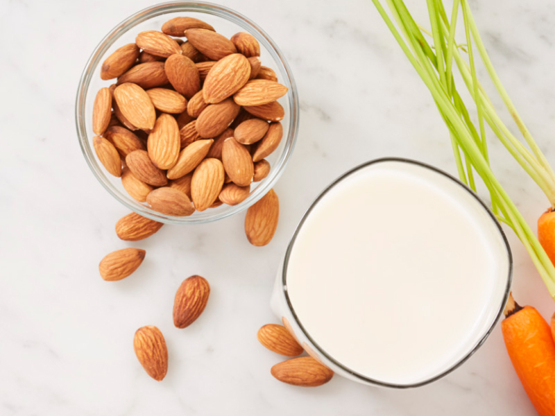 Carrots next to a bowl of almonds and glass of milk Carrots next to a bowl of almonds and glass of milk
