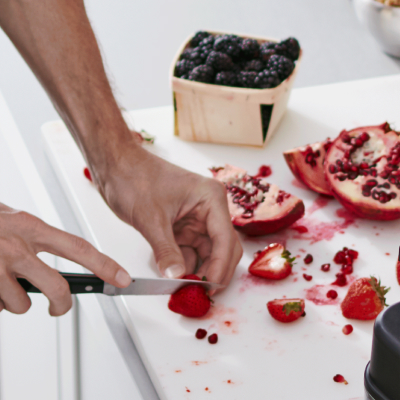 Person slicing fresh fruit on a white cutting board