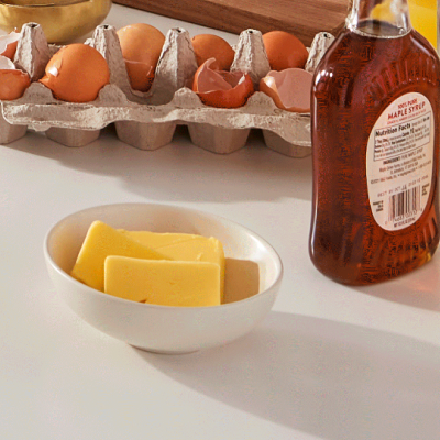 Butter, eggs and maple syrup on a white countertop