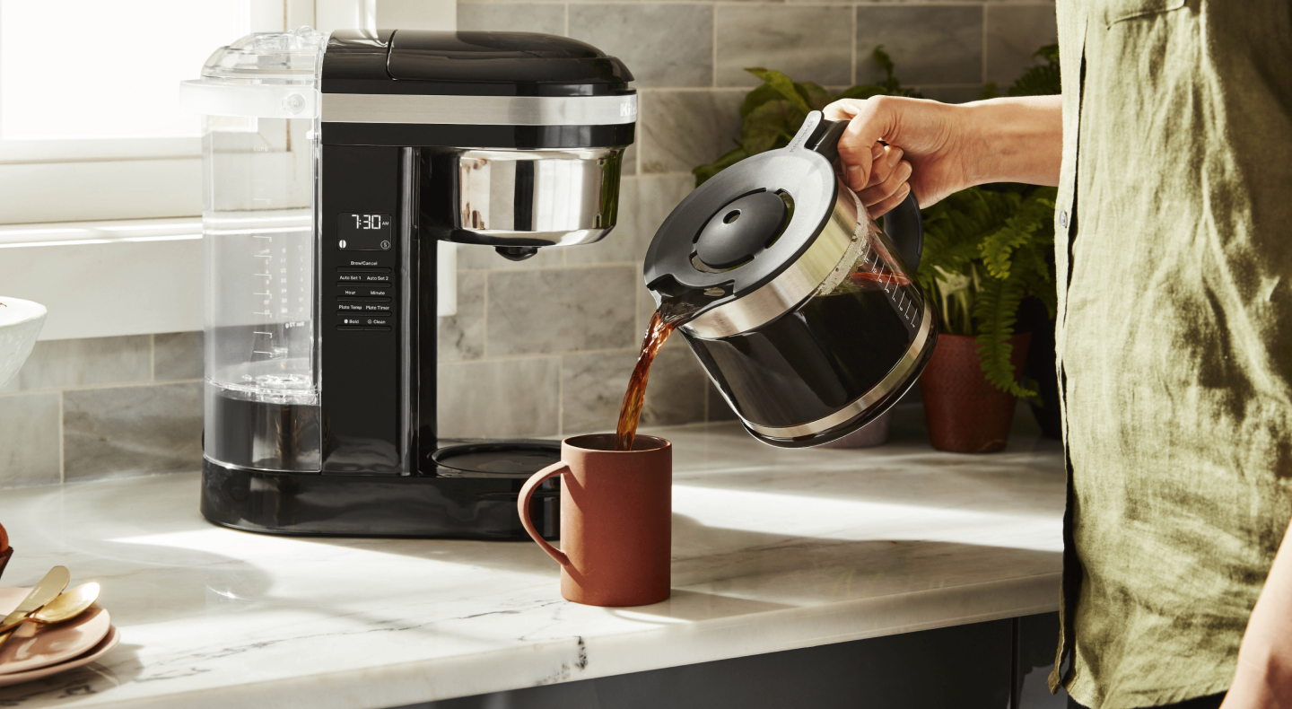 Person pouring coffee from a pot into a mug Person pouring coffee from a pot into a mug