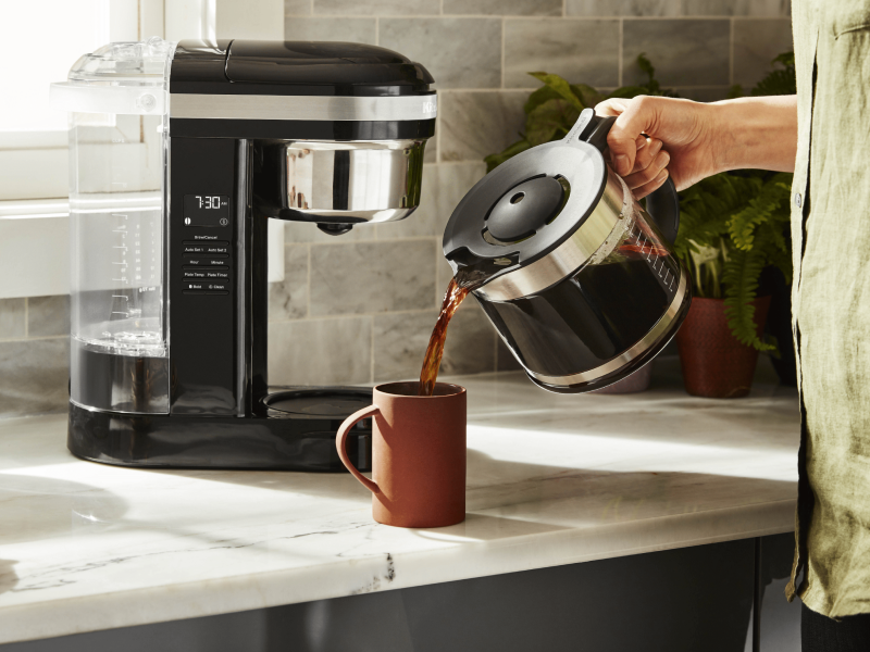Person pouring coffee from a pot into a mug Person pouring coffee from a pot into a mug