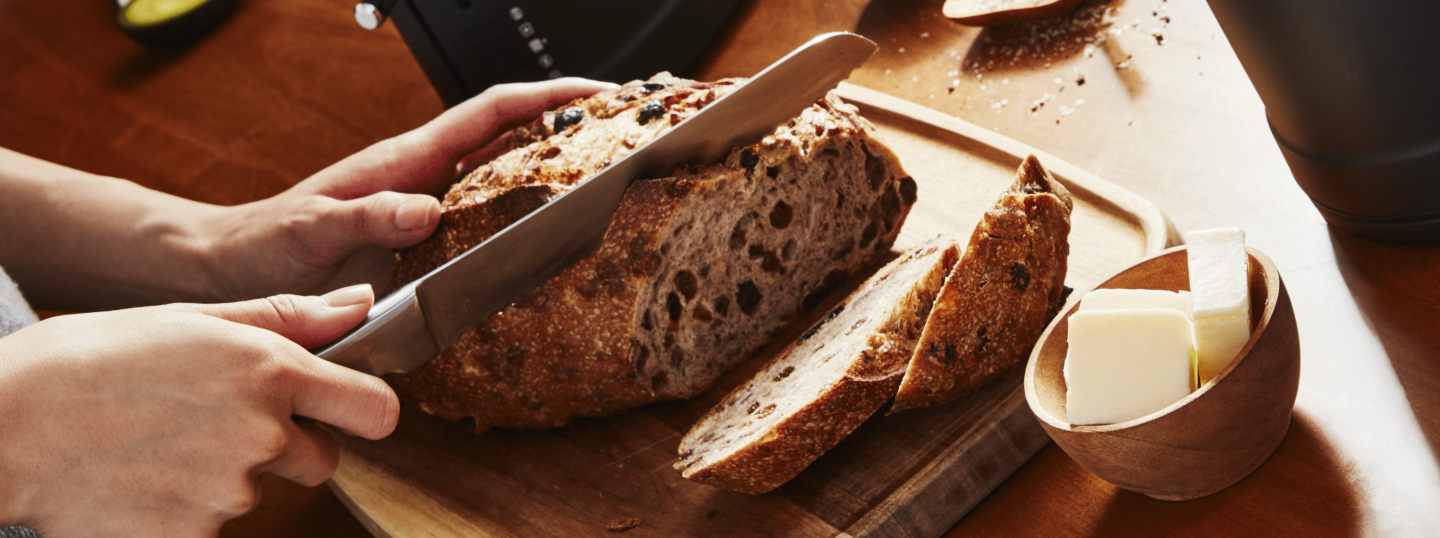 Person slicing freshly baked bread on a cutting board Person slicing freshly baked bread on a cutting board