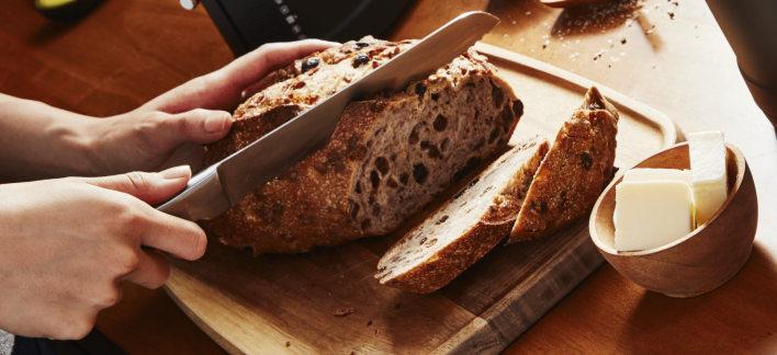 Person slicing freshly baked bread on a cutting board Person slicing freshly baked bread on a cutting board