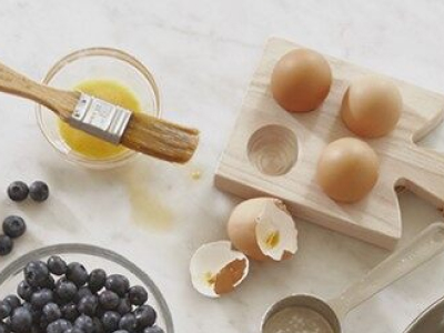 Ingredients including eggs next to egg wash and beside a bowl of blueberries