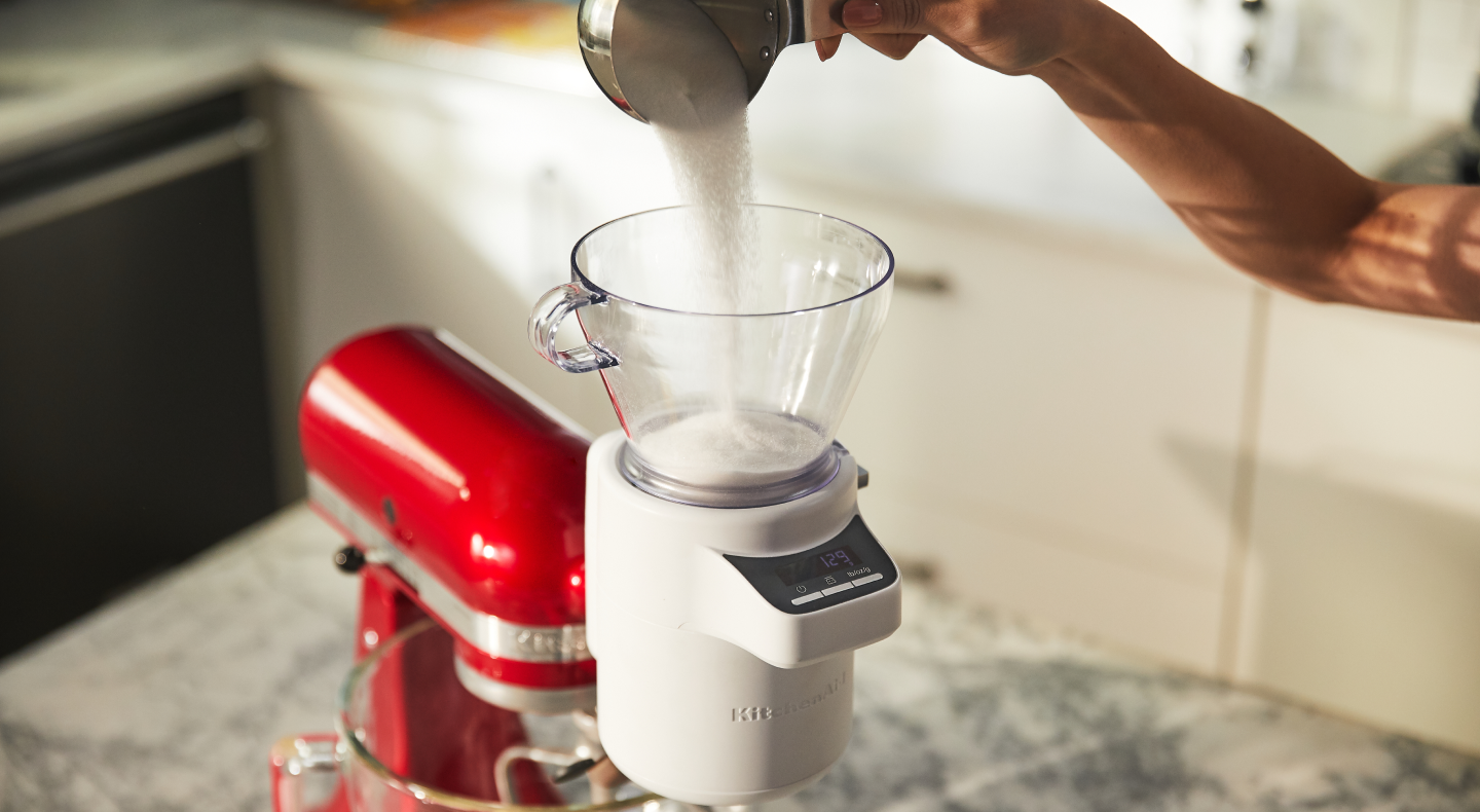 Person pouring ingredients into the KitchenAid® Sifter + Scale Attachment Person pouring ingredients into the KitchenAid® Sifter + Scale Attachment
