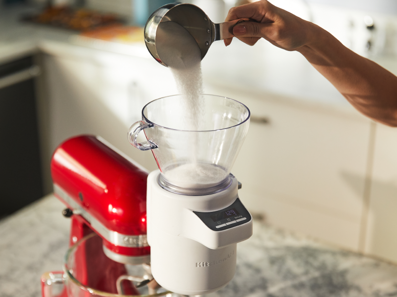 Person pouring ingredients into the KitchenAid® Sifter + Scale Attachment Person pouring ingredients into the KitchenAid® Sifter + Scale Attachment