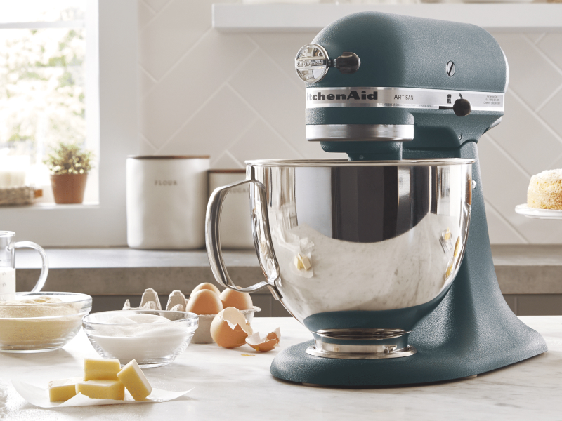KitchenAid® stand mixer in a modern kitchen next to egg shells, butter, sugar and flour.