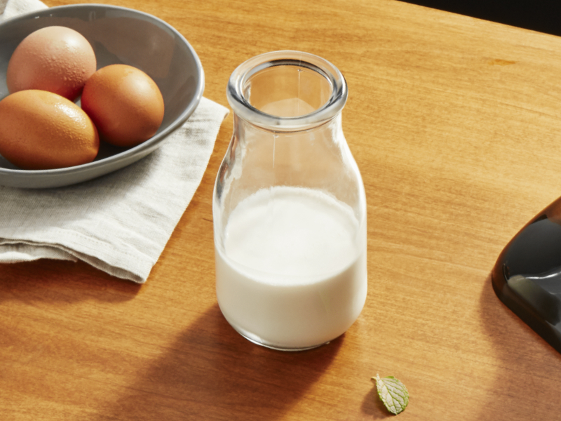 Jar of milk on cutting board next to eggs in a bowl