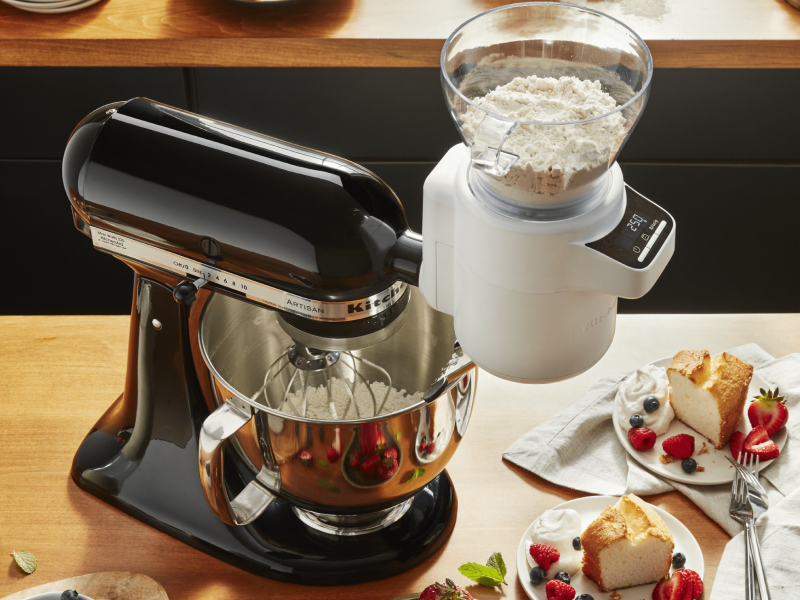 KitchenAid® stand mixer with Sifter + Scale Attachment measuring flour into stainless steel bowl