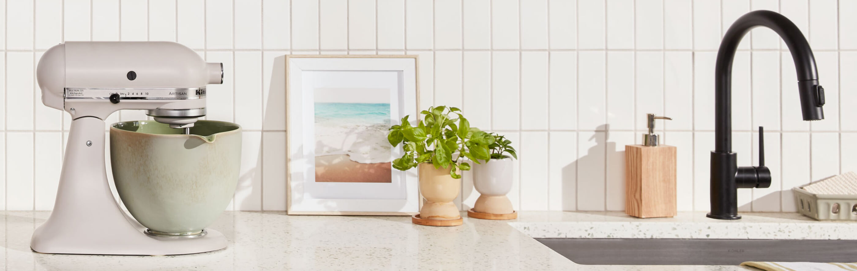 Beige KitchenAid® stand mixer with distressed green mixer bowl on granite countertop