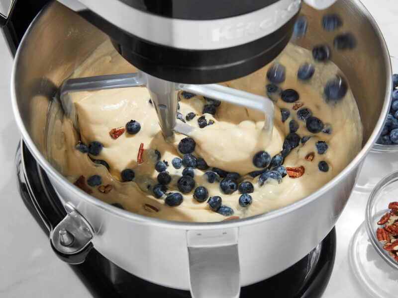 Birds-eye view of black KitchenAid® stand mixer mixing blueberries into batter