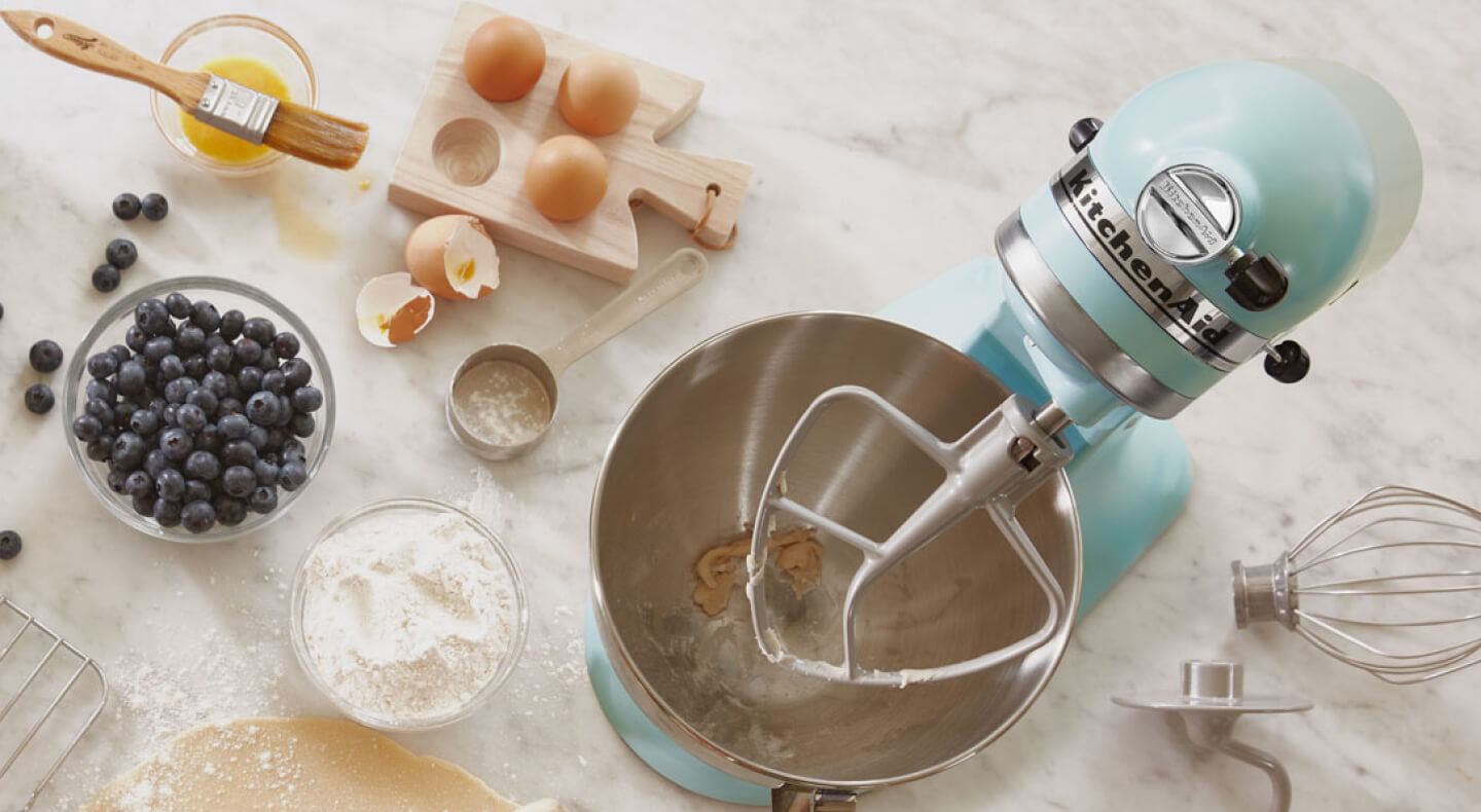 Birds-eye view of light blue stand mixer surrounded by blueberry muffin ingredients Birds-eye view of light blue stand mixer surrounded by blueberry muffin ingredients