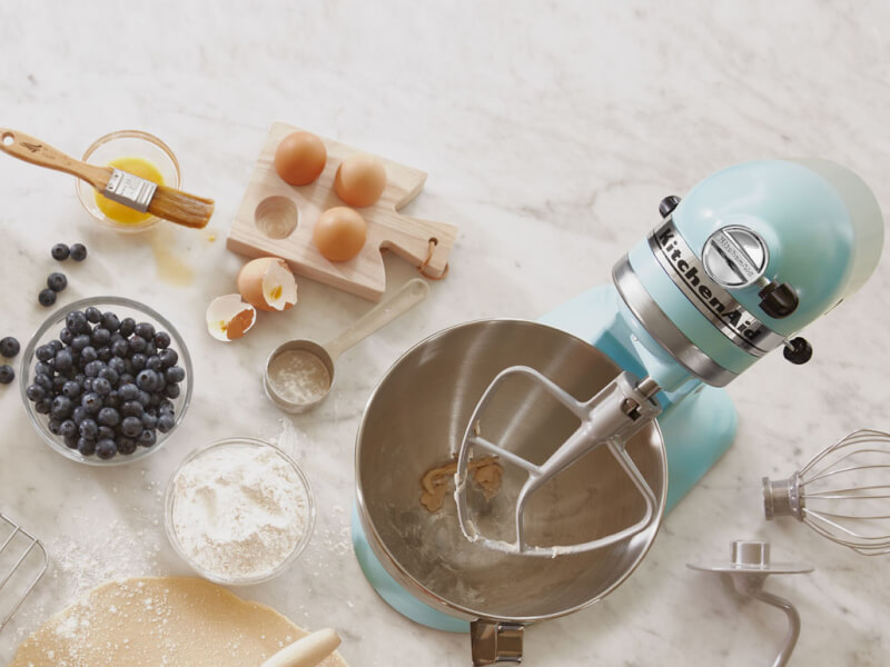 Birds-eye view of light blue stand mixer surrounded by blueberry muffin ingredients Birds-eye view of light blue stand mixer surrounded by blueberry muffin ingredients