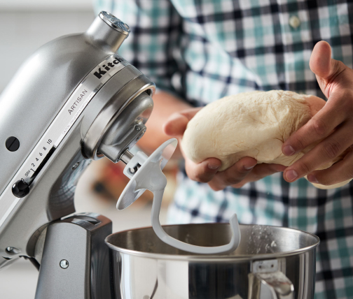 Person shaping dough taken from a stand mixer bowl Person shaping dough taken from a stand mixer bowl