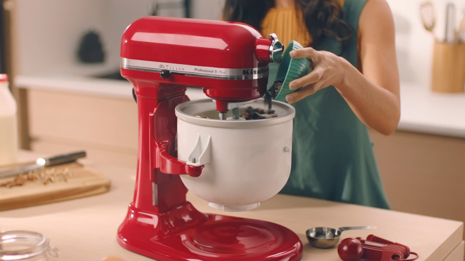 Woman pouring chocolate chips into the bowl of the stand mixer Ice Cream Maker attachment