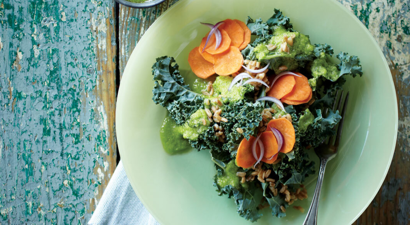 A closeup of a chopped kale salad with sliced carrots and onions. A closeup of a chopped kale salad with sliced carrots and onions.