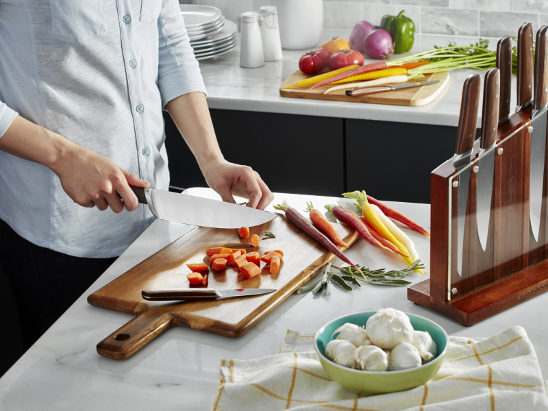 A man chopping carrots on a cutting board in a modern kitchen.