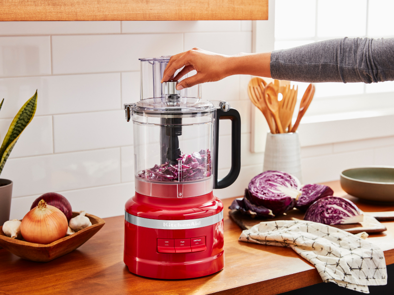 A woman chopping purple cabbage in a KitchenAid® food processor.