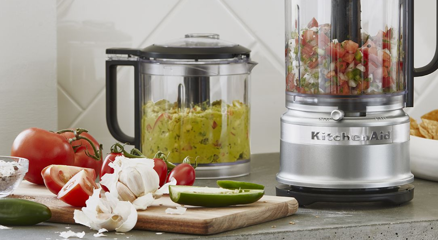 Guacamole and salsa in food processors on counter Guacamole and salsa in food processors on counter