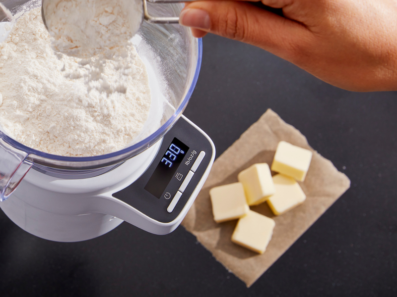 Person adding flour and butter cubes to a bowl